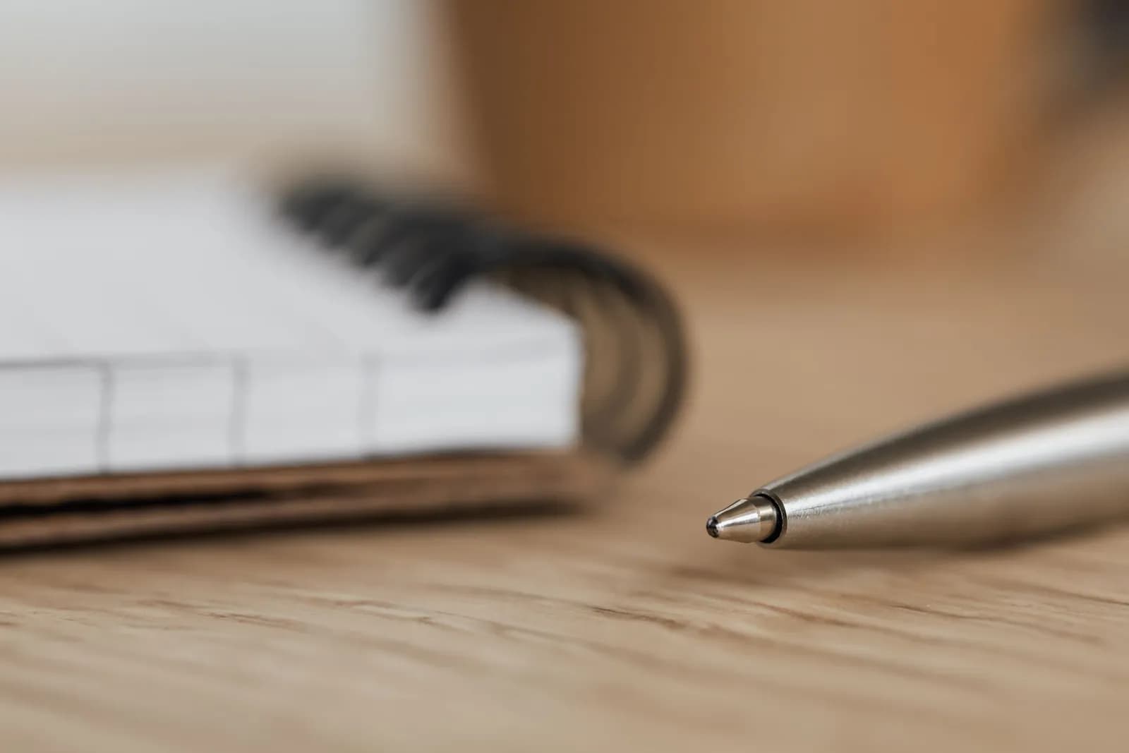 An open ring-bound notebook and pen on a wooden desk