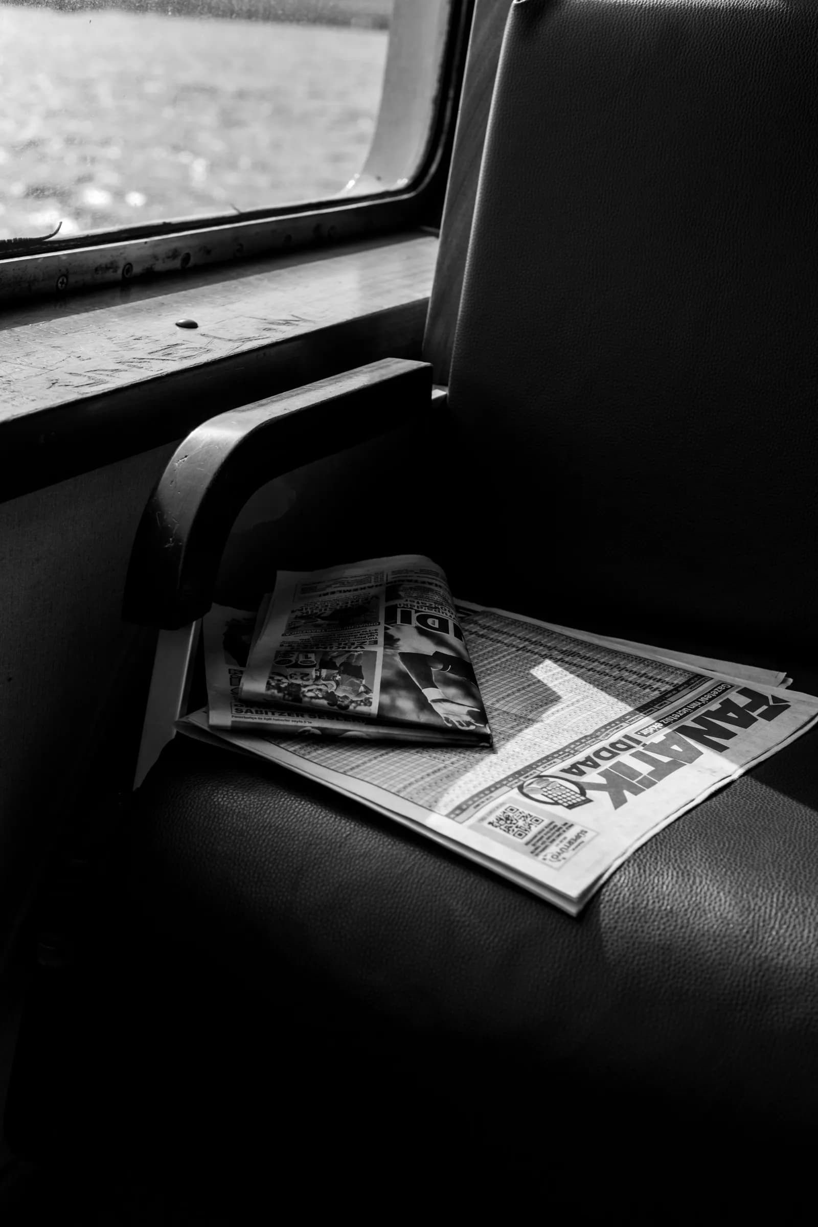 A folded newspaper left on a ferry seat